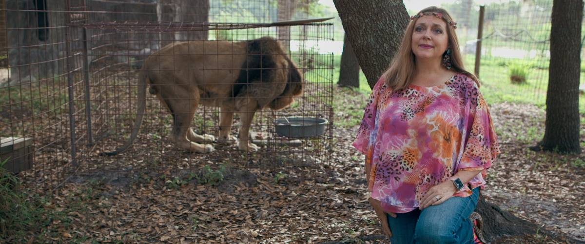 Carole Baskin standing in front of a lion cage