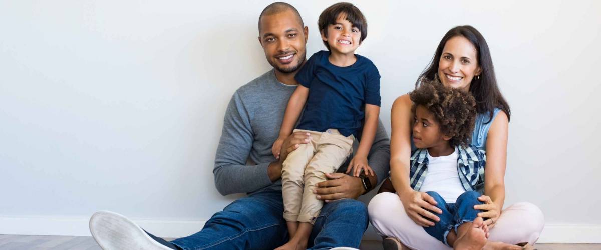 Happy multiethnic family sitting on floor with children.