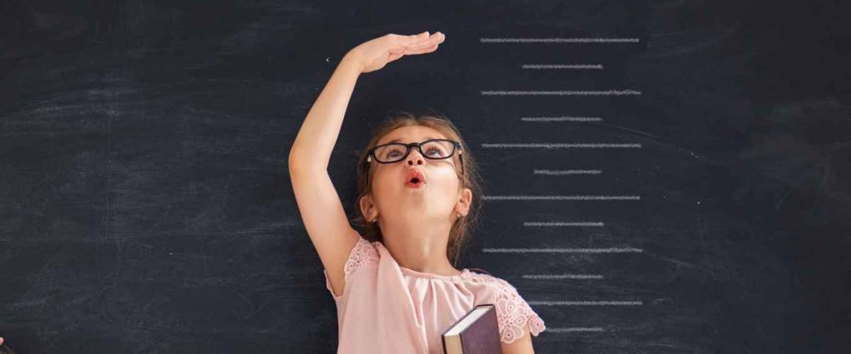 Two children sisters play together. Kid measures the growth on the background of blackboard. Concept of education.