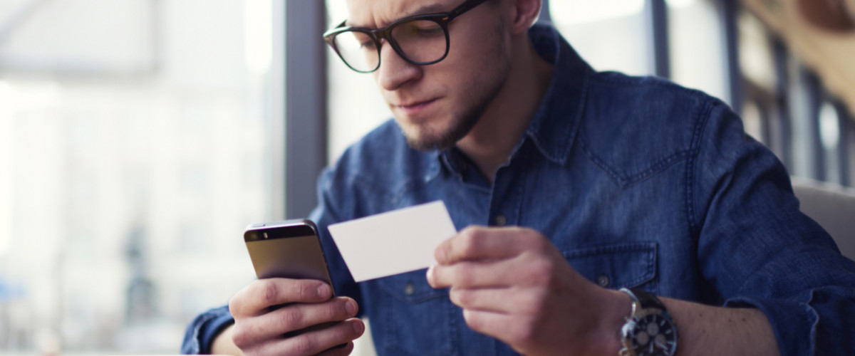 Young man making a purchase on a smart phone using a credit card
