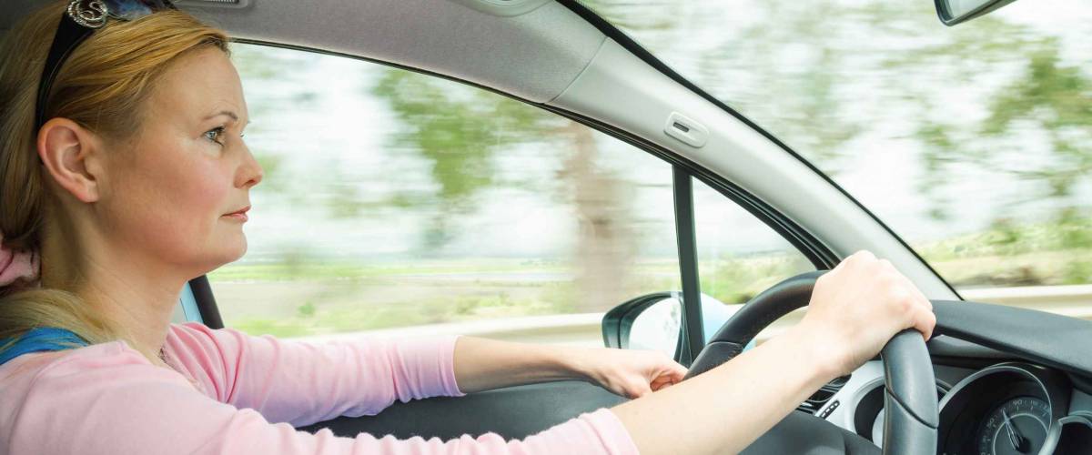 Profile portrait of serious calm woman careful and safe driving car on country road. Stock photo captured in active dynamic motion on high speed with slow shutter and blurred background.