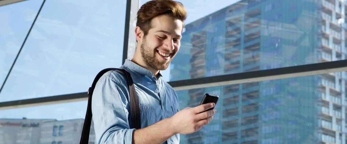 Portrait of an attractive young man walking and looking at mobile phone
