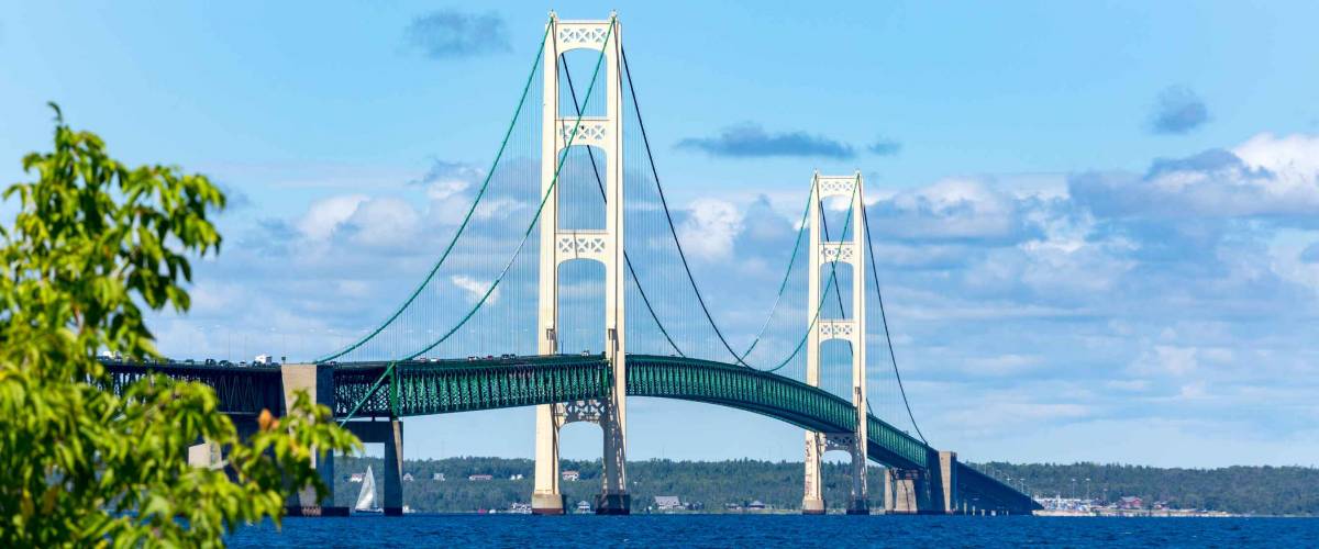 The Mackinac Bridge on a summer day. A suspension bridge spanning the Straits of Mackinac to connect the Upper and Lower Peninsulas of Michigan. Puffy clouds in a blue sky