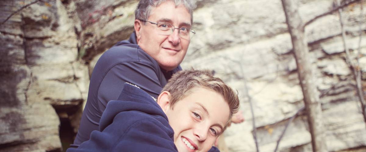 Father and son in front of a rock wall