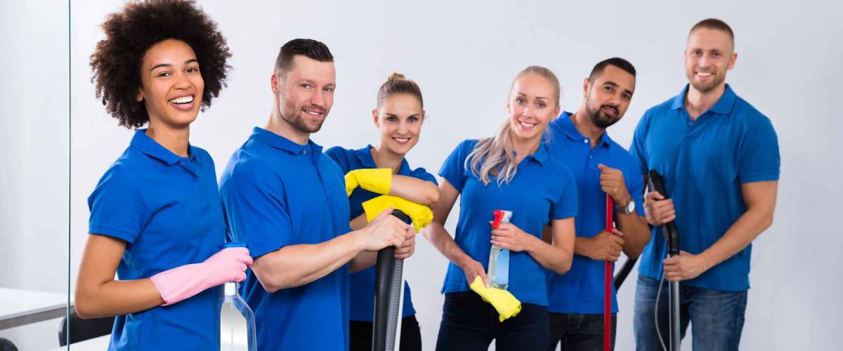 Portrait Of Happy Male And Female Janitors With Cleaning Equipment