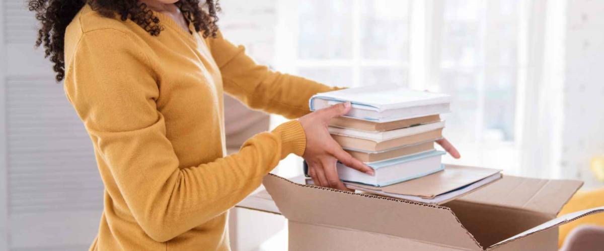 Young girl taking a pile of books out of the box