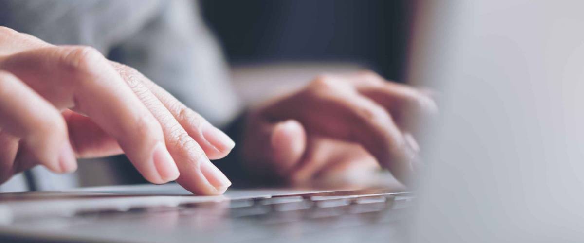Closeup image of a business woman's hands working and typing on laptop keyboard on glass table