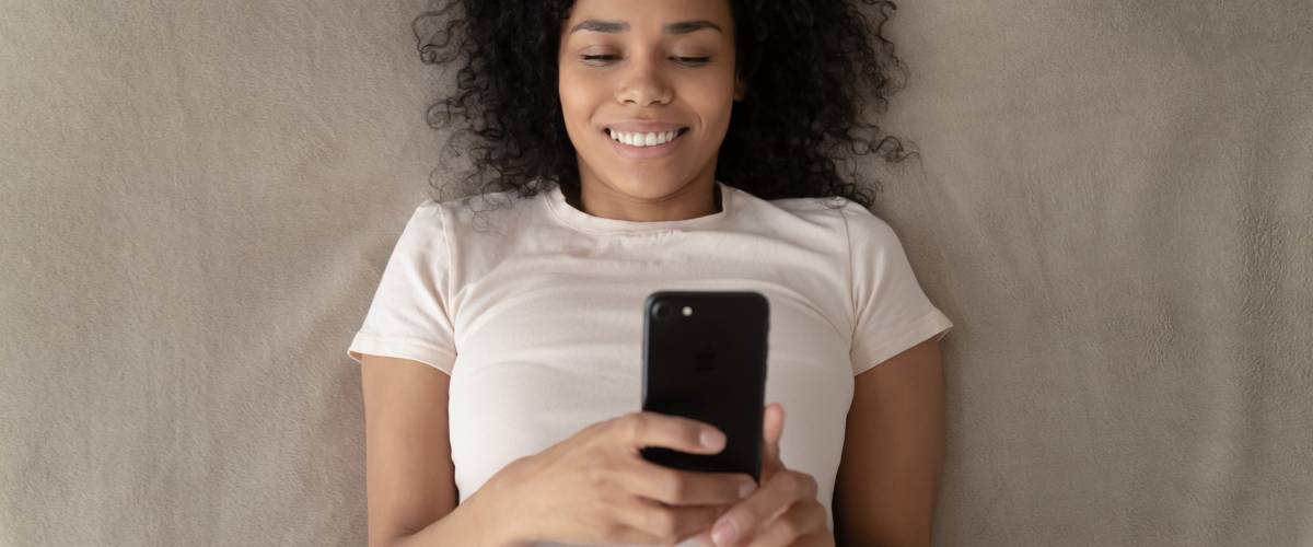 A young woman using her phone while lying down