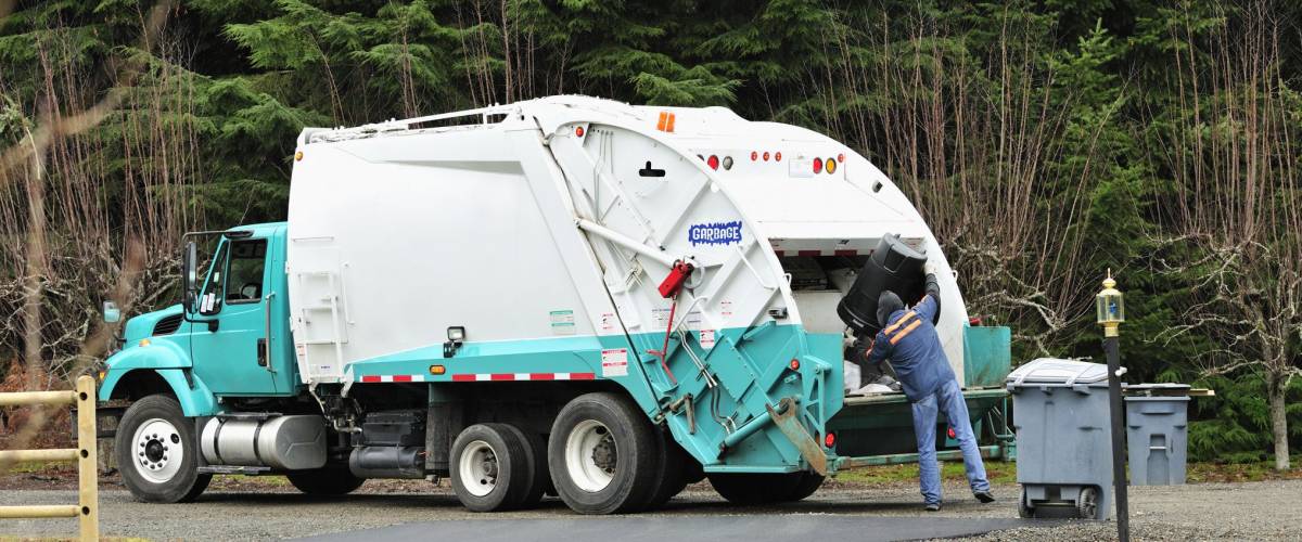 A Sanitation Worker dumps a trash can into a garbage truck.