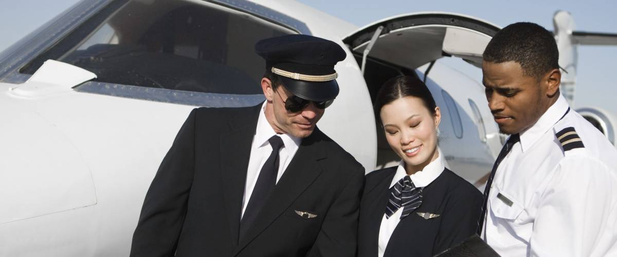 Multiethnic cabin crew members discussing reports together with airplane in the background at airfield