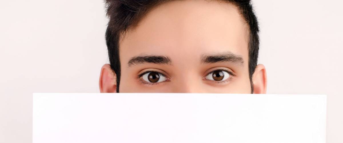Eyes looking over a piece of paper. Man holding a blank white paper.