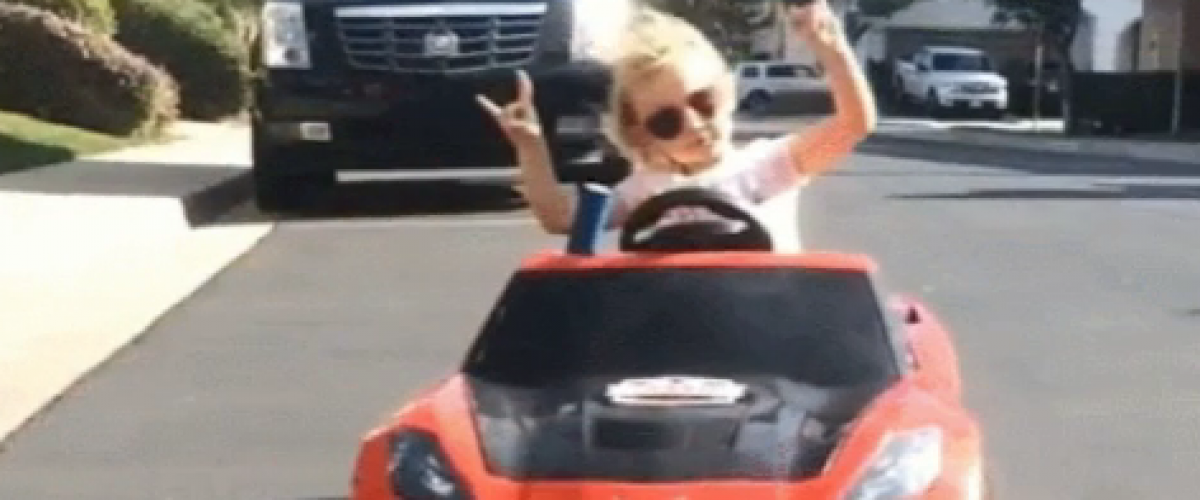 young girl in a car with metal hand gestures