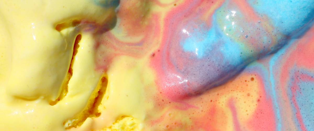 a close up square background of melted pink, blue, and yellow rainbow sorbet ice cream