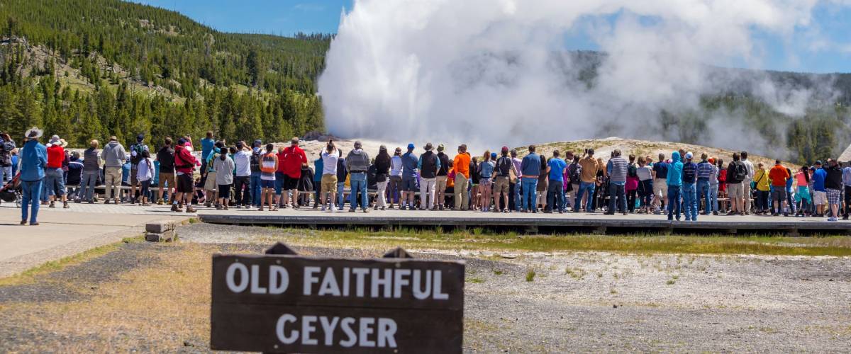 Tourists watching the Old Faithful erupting in Yellowstone National Park, USA