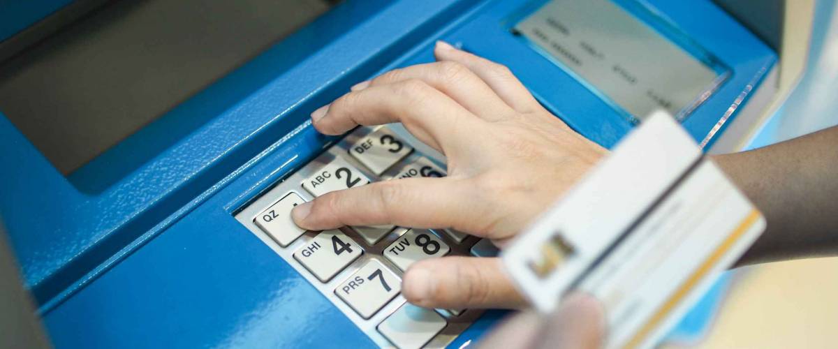 Woman pushing password on button of ATM machine for cash deposit