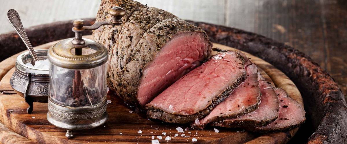 Roast beef on cutting board with saltcellar and pepper mill
