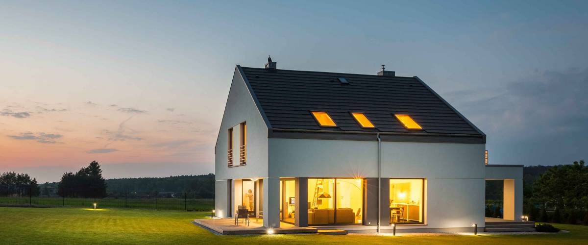 Panoramic photo of modern house with outdoor and indoor lighting, at night
