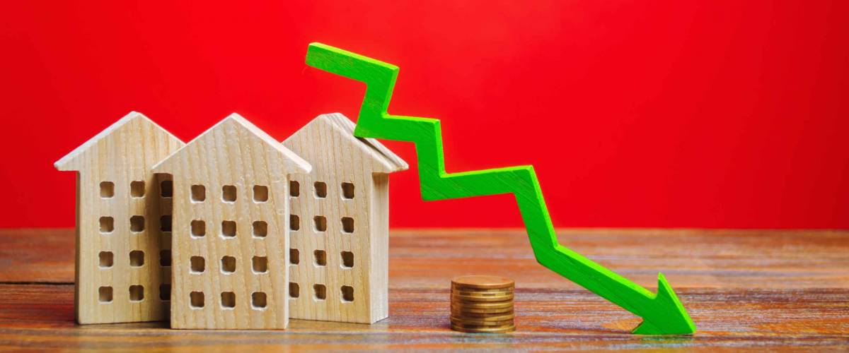 Miniature wooden houses and a green arrow down. The concept of low mortgage rates.
