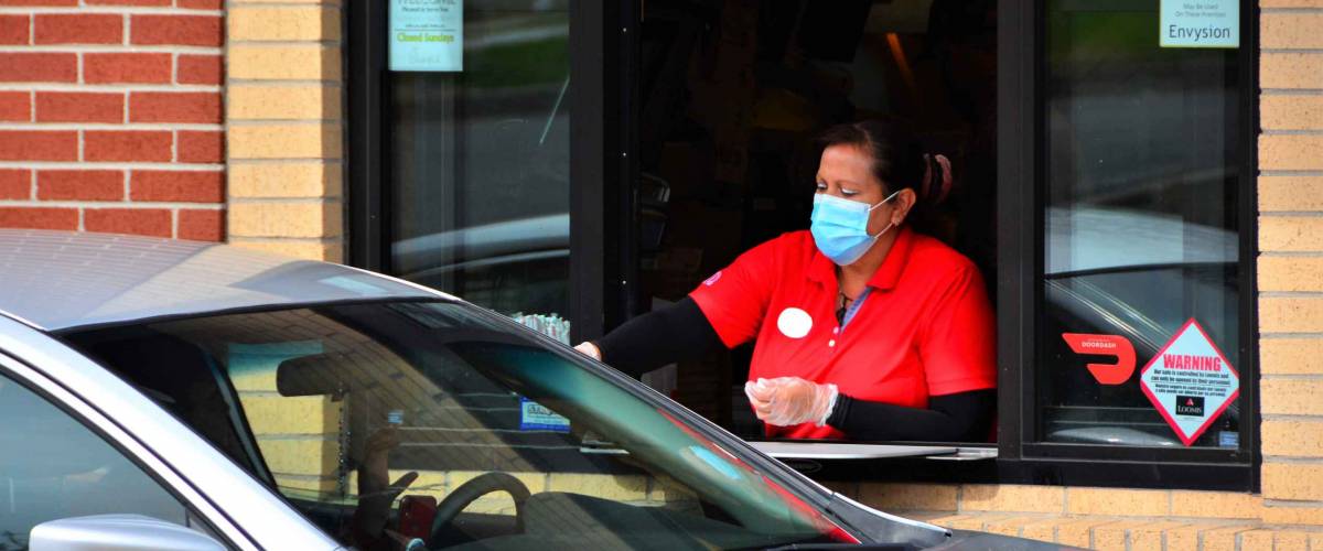 Denver, CO, USA. May 12, 2020. Fast food worker at Chick-Fil-A restaurant in Denver serving food to a drive thru customer while wearing her face mask.