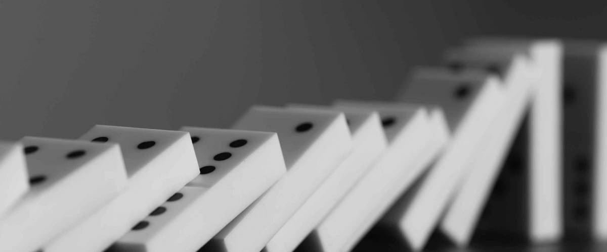Dominoes falling on gray background