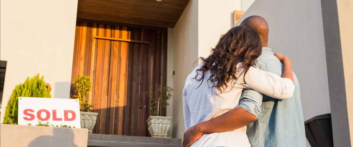 Back view of couple with arms above after buying house