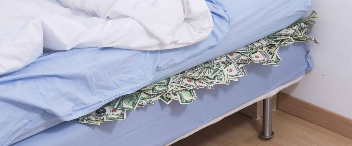 Savings or bank run concept: Hiding US dollars under the mattress