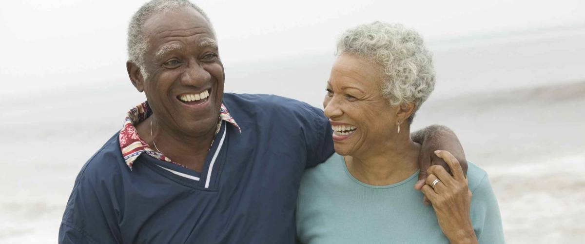Cheerful African American mature couple with arms around at the beach