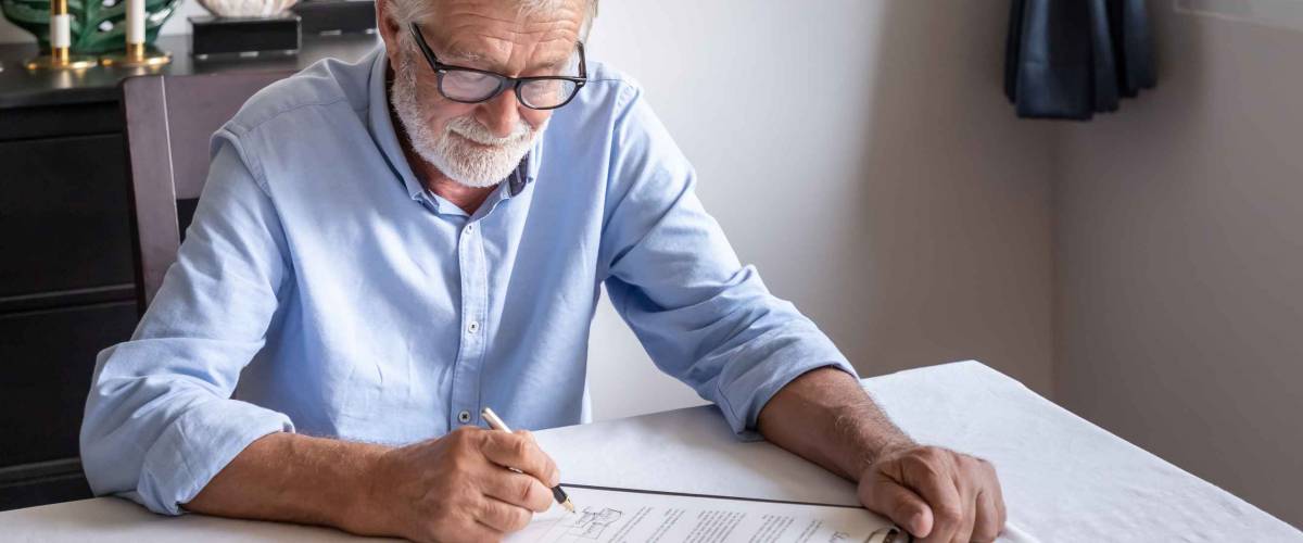 Senior old man elderly examining and signing last will and testament