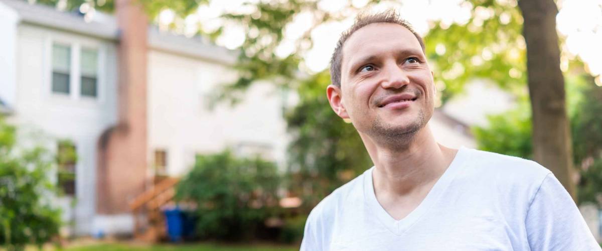 Young man happy smiling homeowner in Herndon, Northern Virginia, Fairfax county residential neighborhood in spring or summer by house backyard