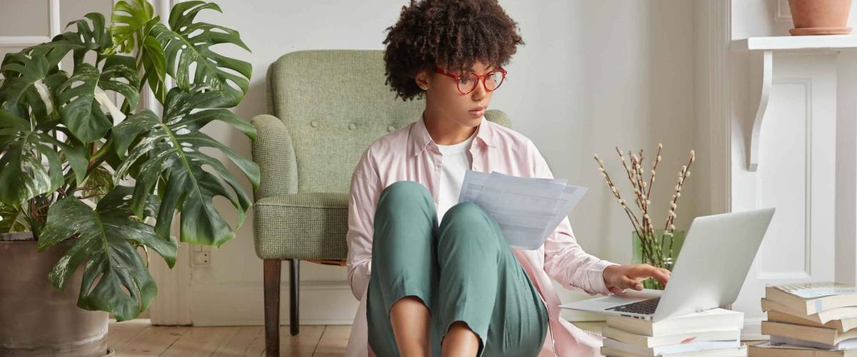 Woman holding paper checks computer