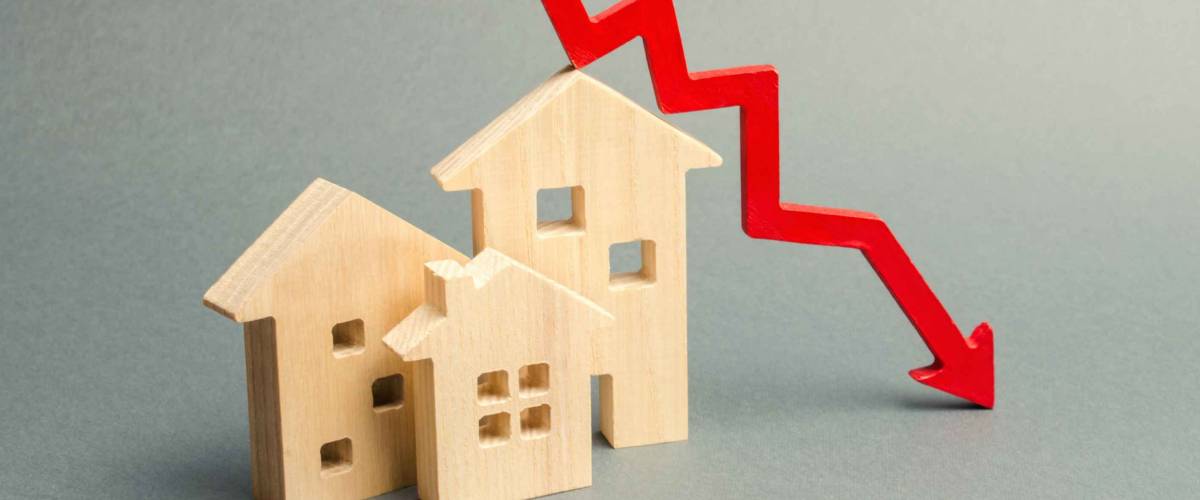 Miniature wooden houses and a red arrow down. The concept of low cost mortgage rates