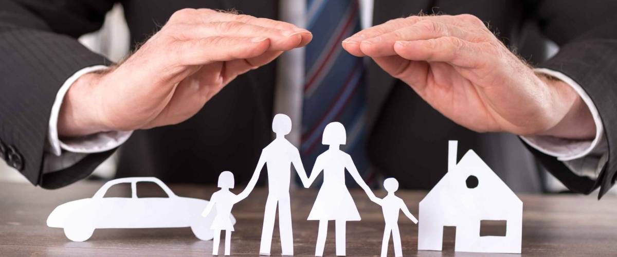 Concept of insurance with hands over a house, a car and a family