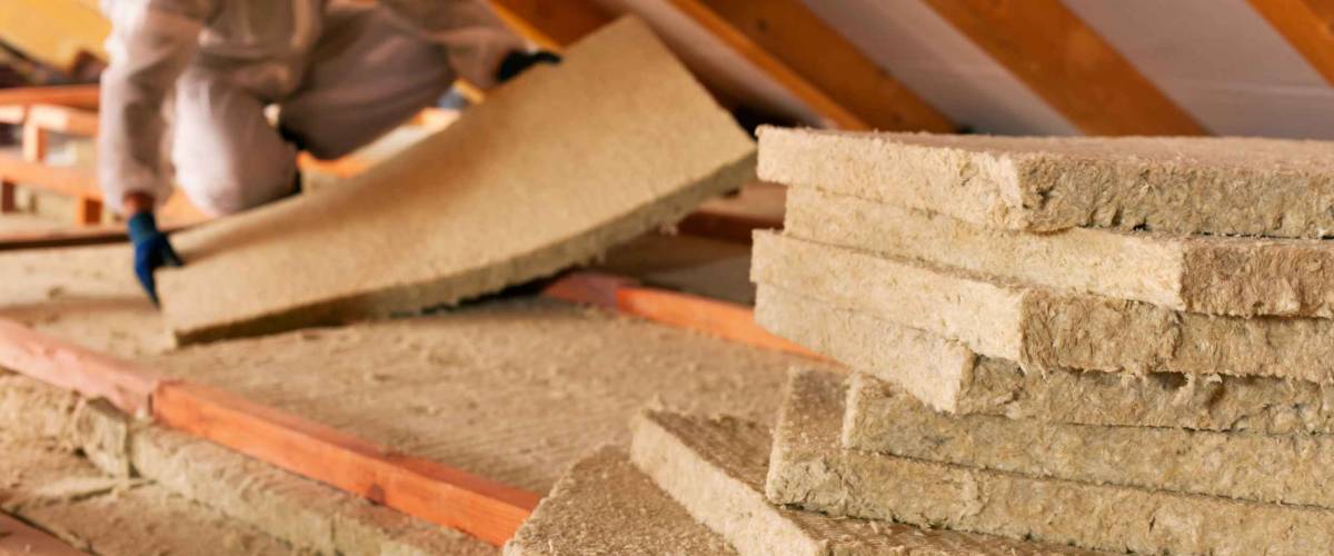 Man installing thermal insulation layer under the roof - using mineral wool panels