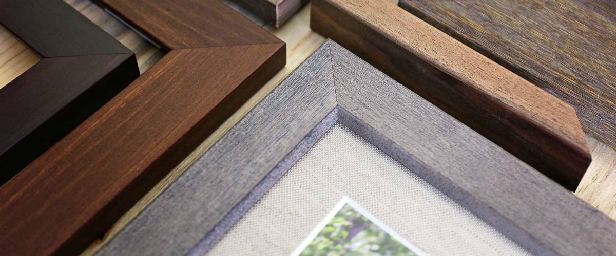 A collection of solid wood photo picture frame corner samples are displayed on a table.