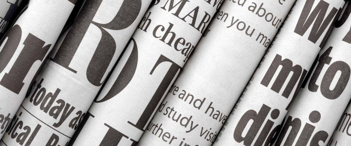Newspaper headlines shown side on in a stack of daily newspapers