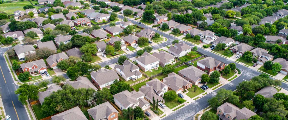 A green neighborhood Suburb houses and homes in new real estate development in Austin , Texas , USA aerial drone view at the corner of the streets