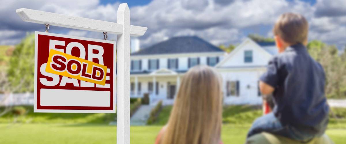 Curious Family Facing Sold For Sale Real Estate Sign and Beautiful New House.