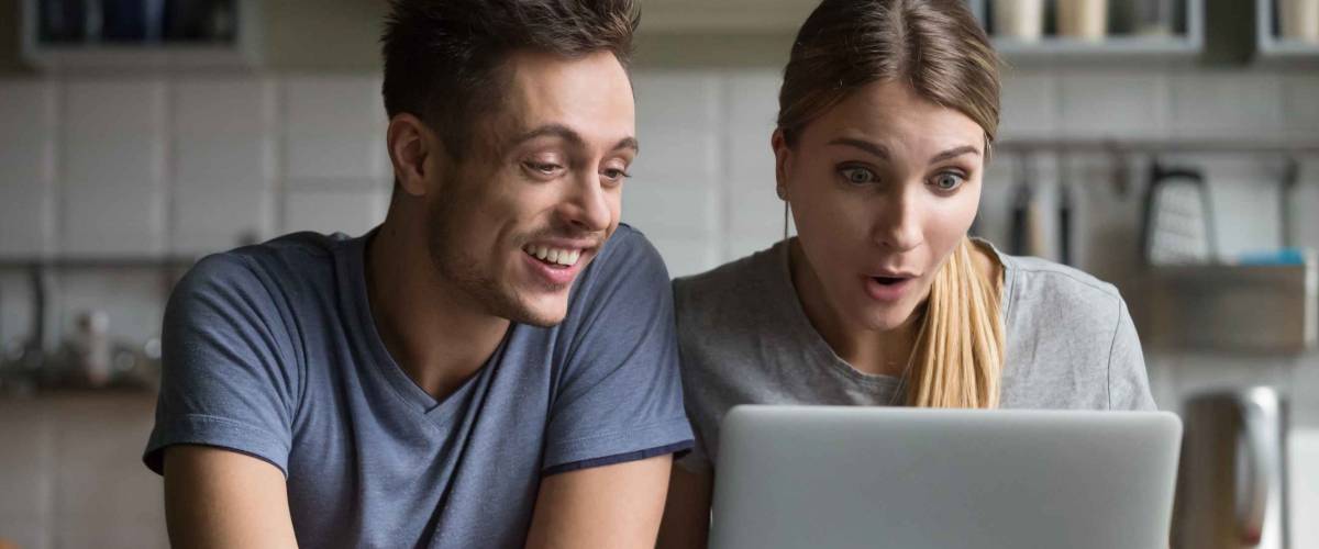 Surprised young couple feeling amazed with online mortgage rates.
