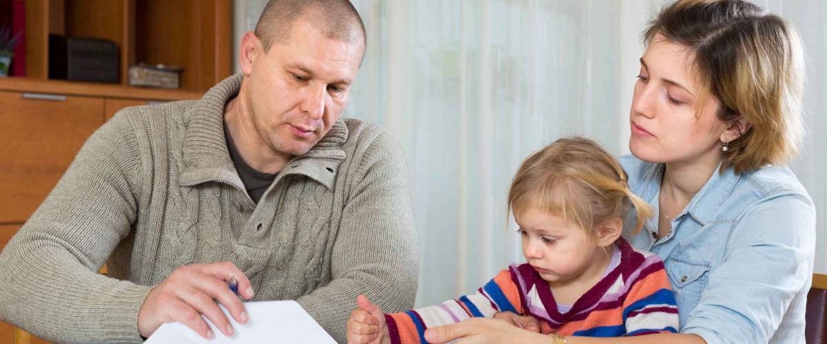 Upset couple with child sitting at the table with financial documents