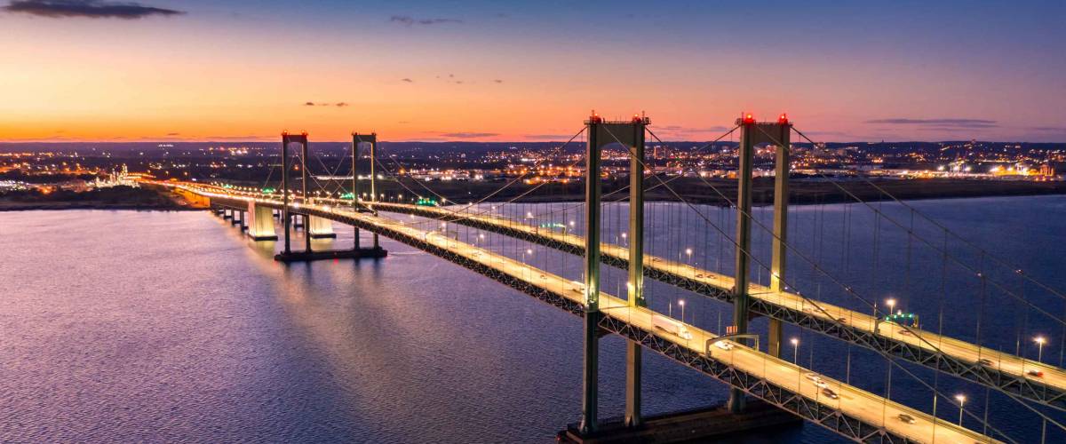 Aerial view of Delaware Memorial Bridge at dusk. The Delaware Memorial Bridge is a set of twin suspension bridges crossing the Delaware River between the states of Delaware and New Jersey