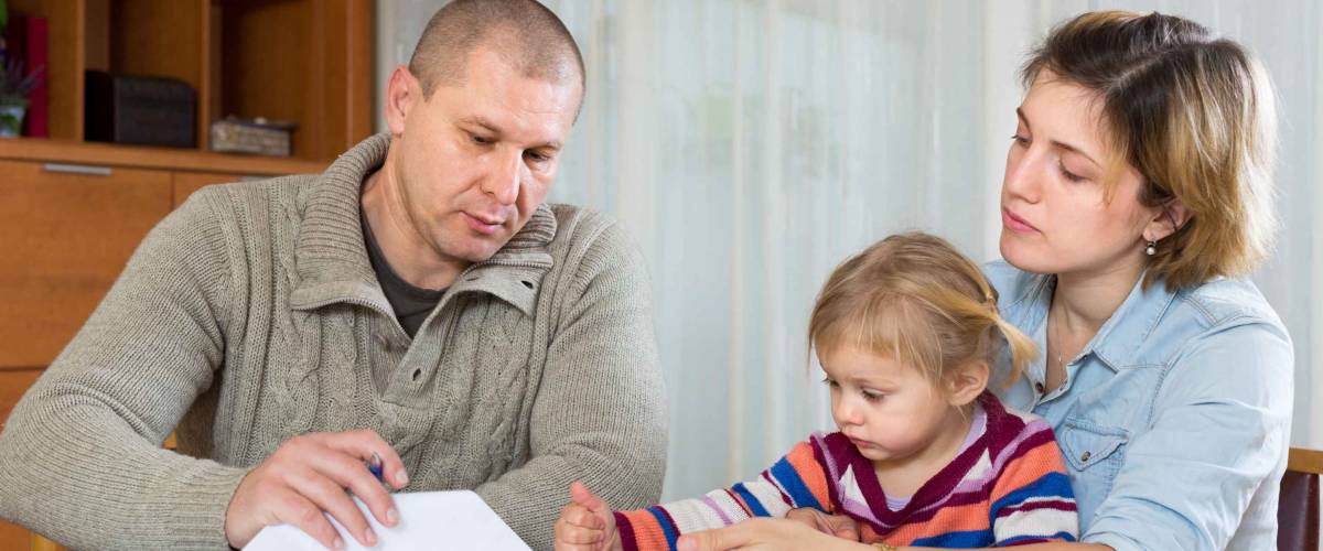 Upset couple with child sitting at the table with financial documents