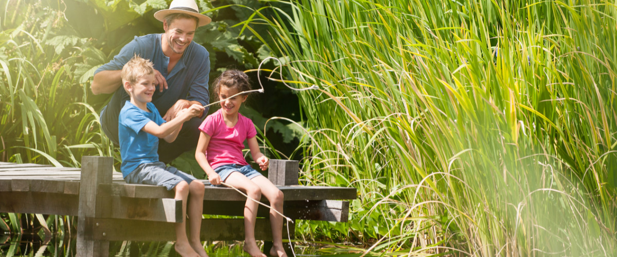 Children fishing with their father on a dock