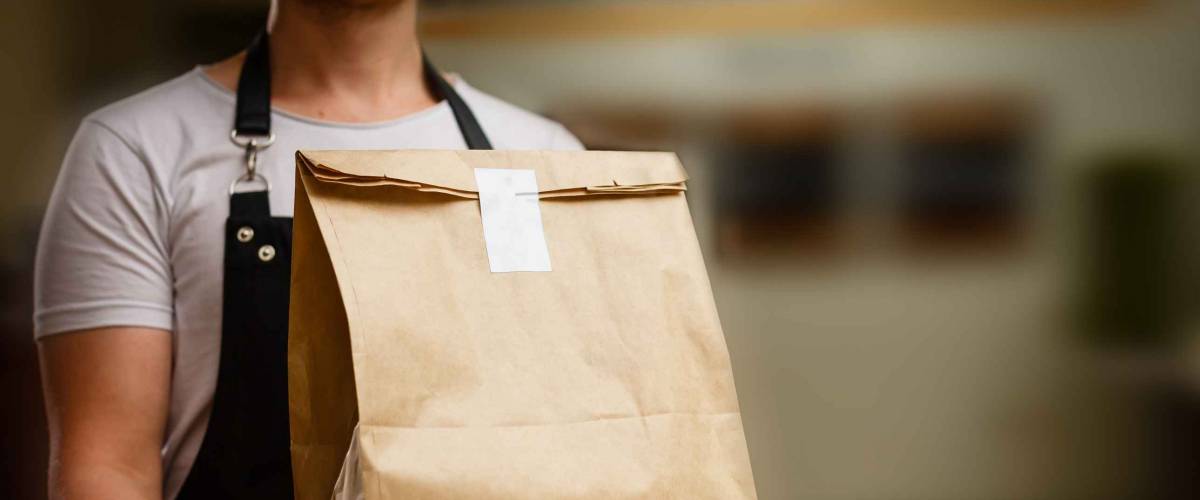 Diverse of paper containers for takeaway food. Delivery man is carrying