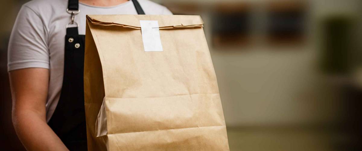 Diverse of paper containers for takeaway food. Delivery man is carrying