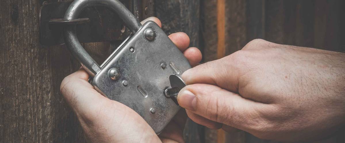 Hands with old door lock and a key. Wooden doors. Vintage style.