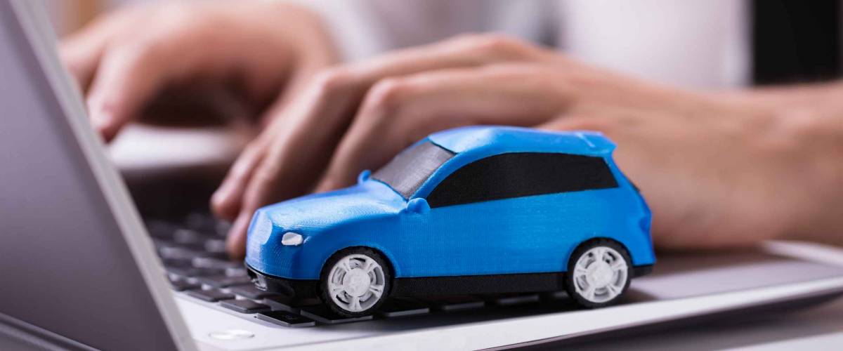 Close-up Of A Small Blue Car On Laptop Keypad
