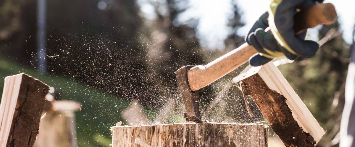 Detail of two flying pieces of wood on log with sawdust. Man is chopping wood with vintage axe. Frozen moment.