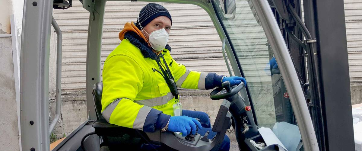 coronavirus : man with protective mask and gloves drives the forklift