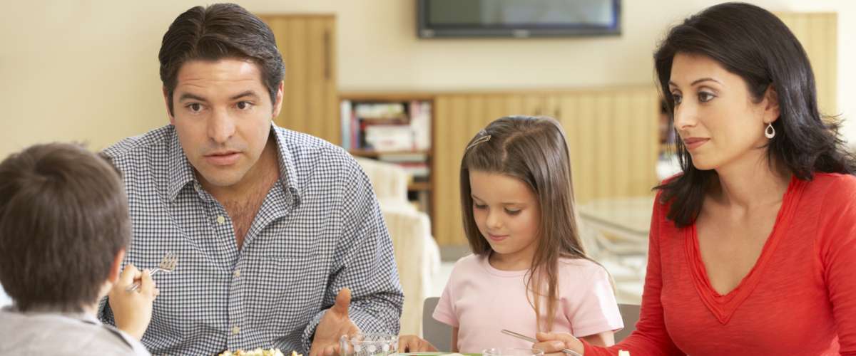 Young family enjoying a meal at home and having a conversation