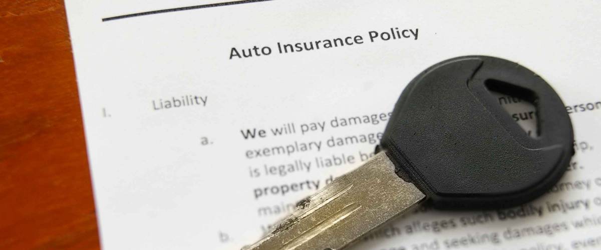 Closeup of a car key on an auto insurance policy